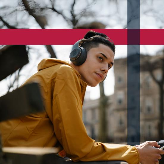 Foto af ung mand, der lytter til lydbog på en bænk