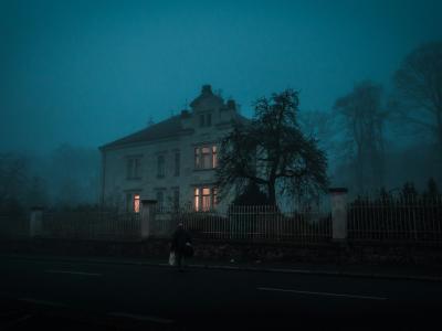 Billede af et hus i tåge med lys i vinduerne